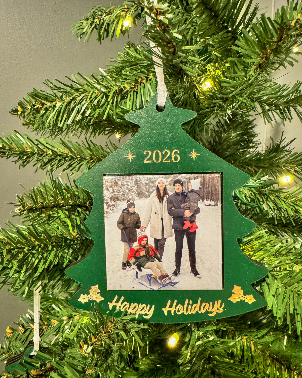 2026 green Christmas tree photo magnet ornament hanging on a lit Christmas tree