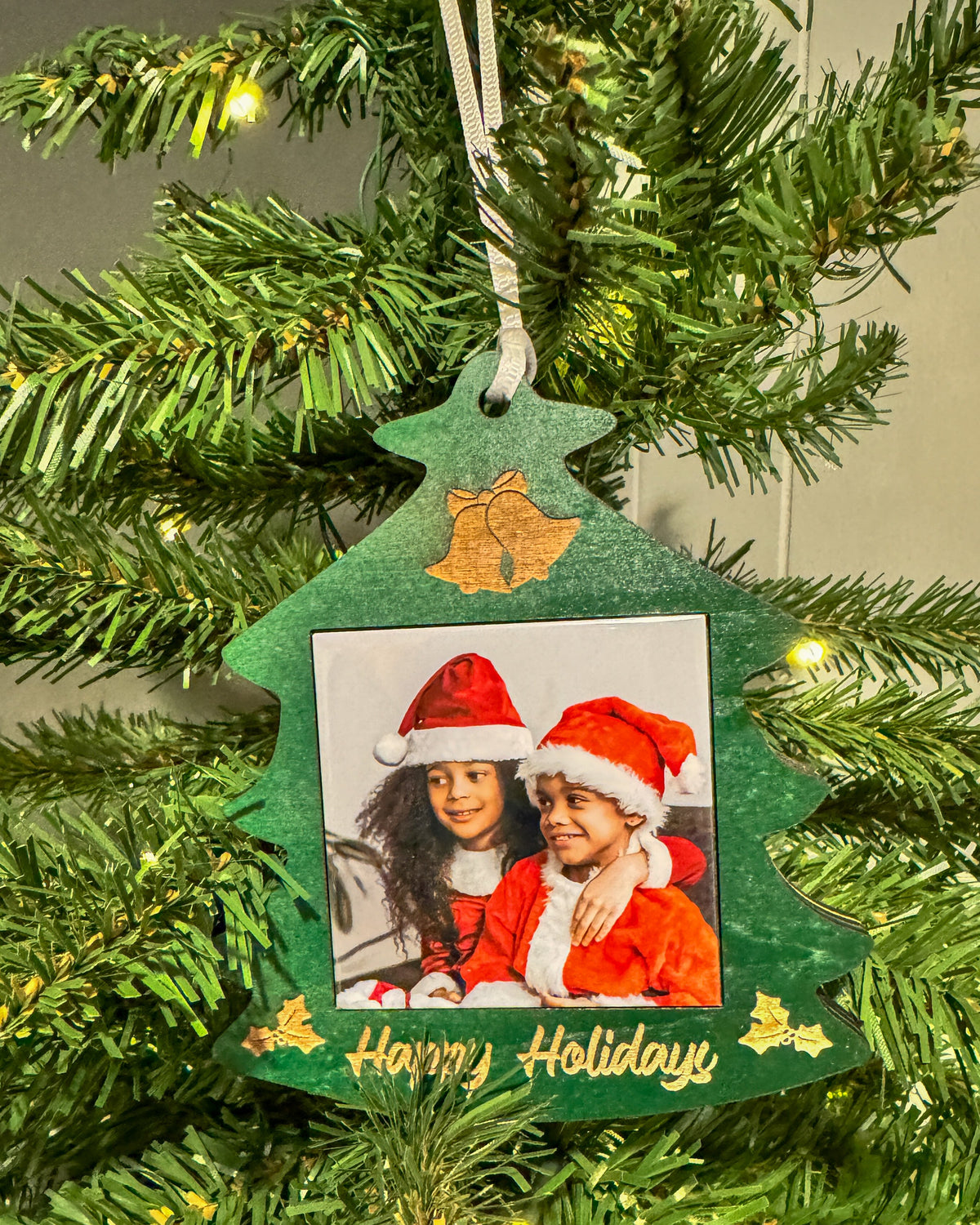 Classic green Christmas tree photo magnet ornament hanging on a lit Christmas tree