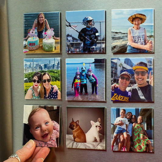 Hand placing a photo magnet into a grid of custom magnets showing family memories including birthdays, travel, pets, and everyday moments