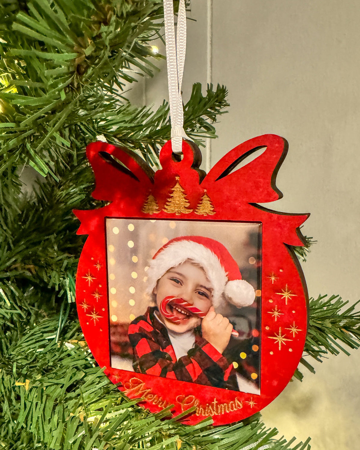 Red Merry Christmas photo magnet ornament hanging on a Christmas tree