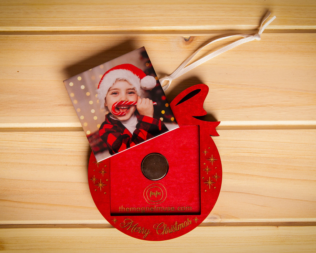 Removable custom photo magnet shown outside a red Merry Christmas wooden ornament